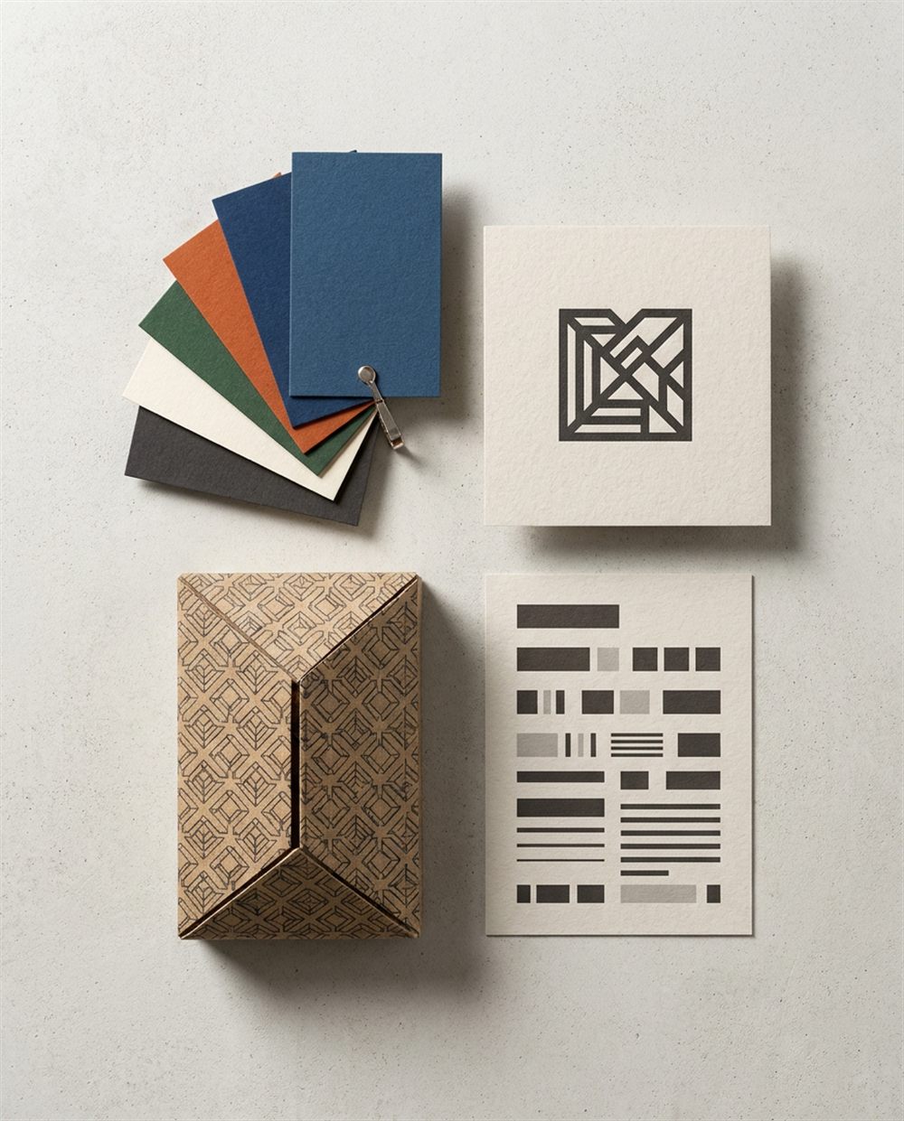 O cutie cu motive geometrice, o carte poștală pătrată cu un logo abstract negru, o carte poștală cu dreptunghiuri negre și șase mostre de hârtie colorată așezate pe o suprafață deschisă la culoare.