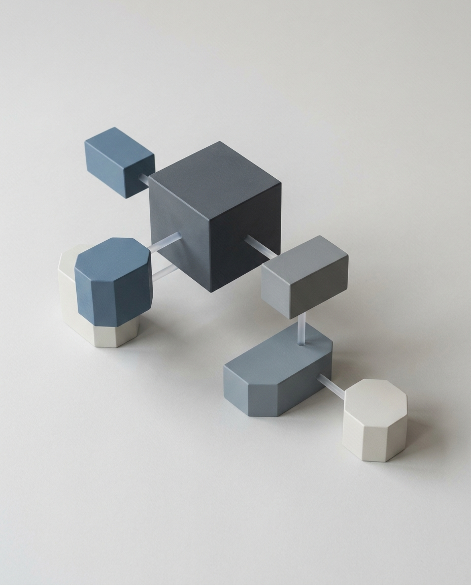 O sculptură geometrică alcătuită dintr-un cub central de culoare gri închis, legat prin tije de prisme octogonale și dreptunghiulare din jur, în nuanțe de gri, albastru și alb, toate dispuse pe o suprafață plană și deschisă la culoare.