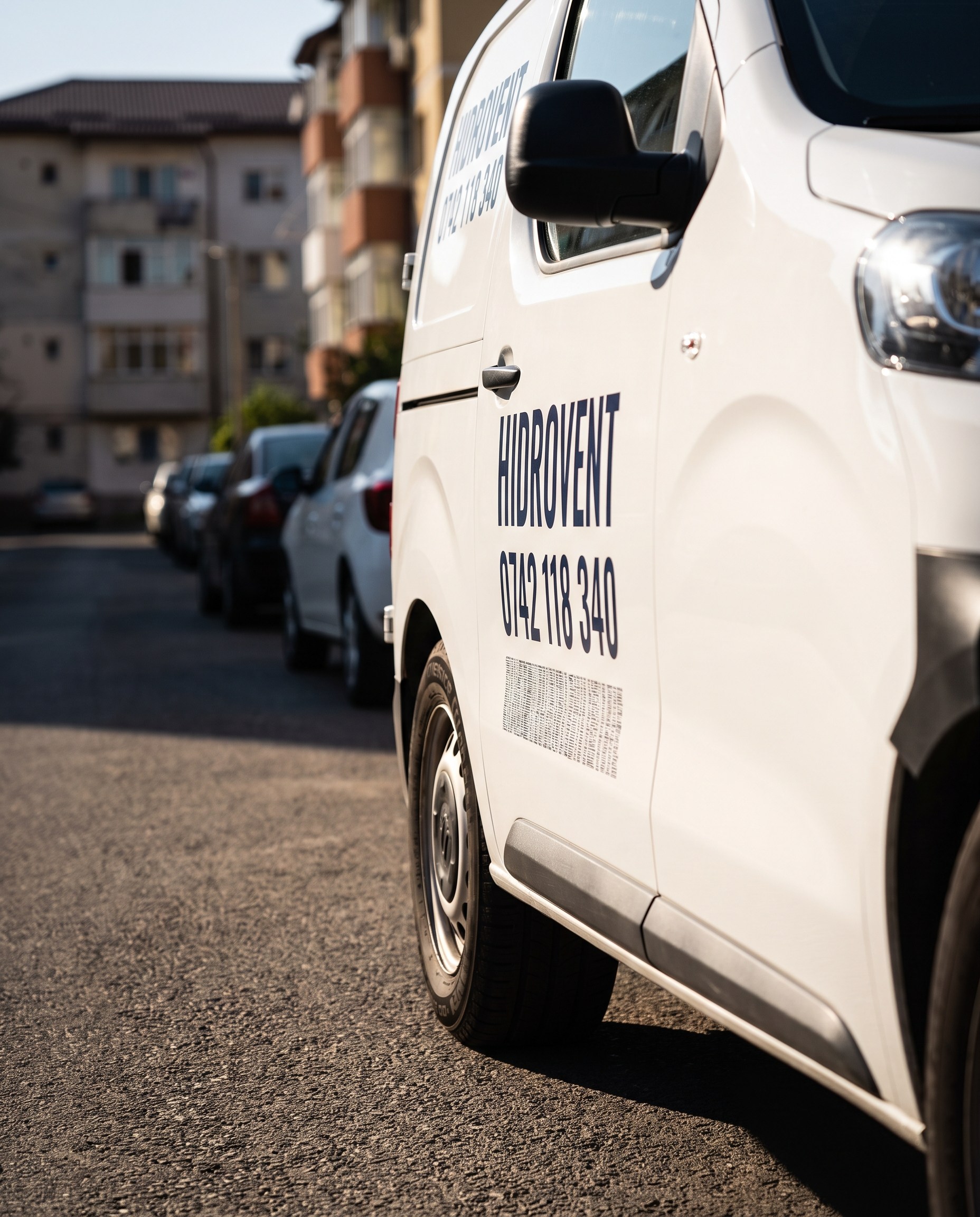 Duba unei firme, fotografiata de la nivelul asfaltului: numele si numarul de telefon se citesc, lista de servicii de dedesubt e un bloc ilizibil